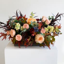 Peach roses and pale yellow flowers in a low rectangular container