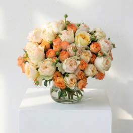 Peach and cream roses arranged in a clear glass vase