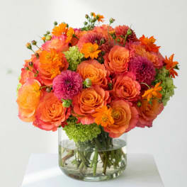 Orange and pink flower bouquet in a clear glass vase