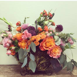 Basket arrangement of orange and pink roses with purple allium and white blooms