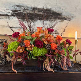 Large floral centerpiece with orange and magenta blooms in a low container