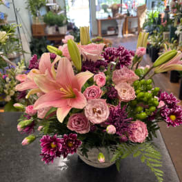 Pink lilies and mixed pink-purple flowers arranged in a white basket