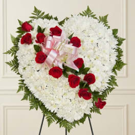 Heart-shaped white chrysanthemum arrangement with red roses and pink ribbon