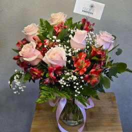 Bouquet of pale pink roses and red alstroemeria in a glass vase