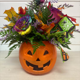 Halloween bouquet in a jack-o'-lantern container with a rainbow rose