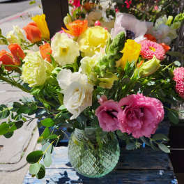 Mixed bouquet in a glass vase with pink, yellow, white, and orange flowers