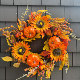 Autumn wreath with sunflowers, pumpkins, and berries on a dark wall