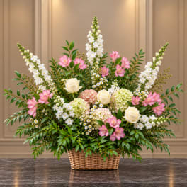 Pink and white mixed flower arrangement in a wicker basket