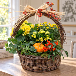 Fall basket arrangement with yellow flowers, a pumpkin, and orange berries