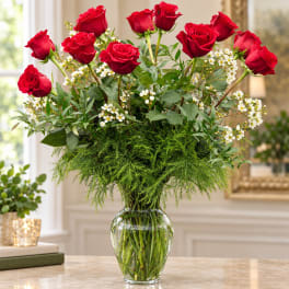 Red roses arranged in a clear glass vase with white filler flowers