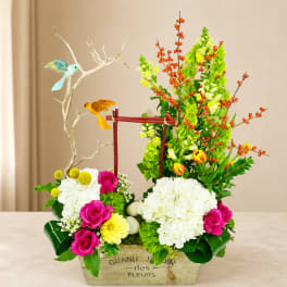 Colorful floral arrangement in a wooden box with birds and branches