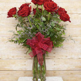 Red roses in a glass vase with a red ribbon bow