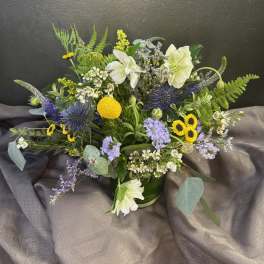 Mixed bouquet with white lilies, yellow blooms, and purple flowers in a vase