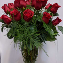 Bouquet of red roses in a glass vase with greenery