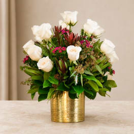 White roses arranged in a gold vase with pink accents