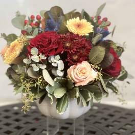 Mixed bouquet in a white vase with red, peach, and yellow blooms