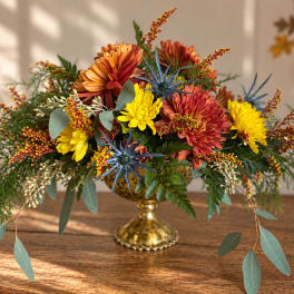 Autumn floral arrangement with chrysanthemums in a gold pedestal vase