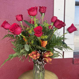 Red roses arranged in a clear glass vase with a decorative ribbon