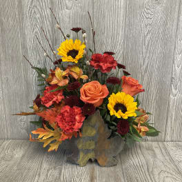 Autumn floral arrangement with sunflowers, roses, and carnations in a rustic vase