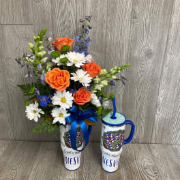 Orange roses and white daisies in a tall travel tumbler with a blue ribbon.