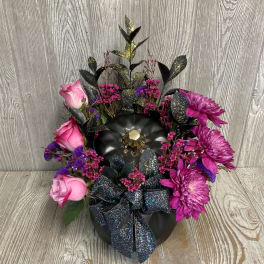 Pink roses and purple mums arranged in a black container with a glittery bow