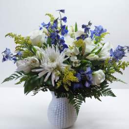 White and blue mixed flower arrangement in a textured white vase