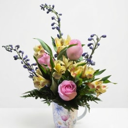 Pink roses and yellow alstroemeria in a floral mug vase