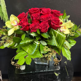 Red roses with pale yellow orchids in a glass vase