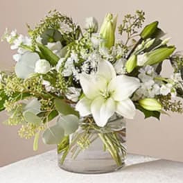 White lilies and green buds in a clear glass vase