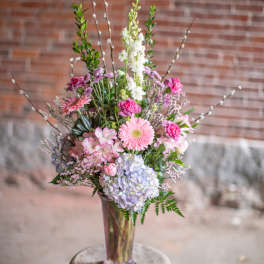Tall pastel bouquet in a clear glass vase on a stool