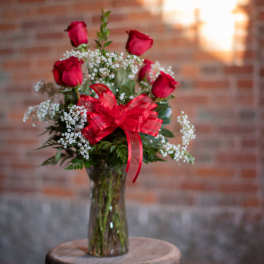 Bouquet of red roses and baby's breath in a glass vase with a red bow