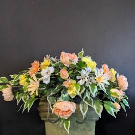 Peach and yellow floral arrangement in a stone urn