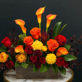 Orange calla lilies and red roses arranged in a rectangular box