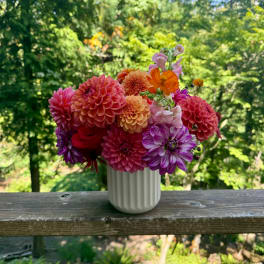 Colorful bouquet of dahlias and snapdragons in a white vase