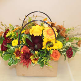 Mixed autumn bouquet in a tan handled box with yellow, orange, and burgundy flowers