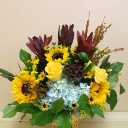 Sunflower and yellow rose arrangement in a printed cup vase