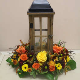 Lantern centerpiece surrounded by orange, yellow, and burgundy flowers