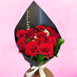 Bouquet of red roses wrapped in black paper with a white ribbon