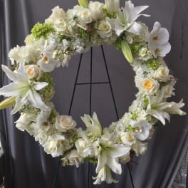 White floral wreath with roses and lilies on a stand