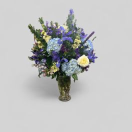 Mixed blue and purple flower arrangement in a glass vase