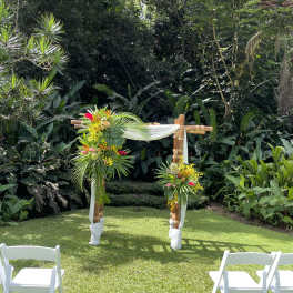 Tropical floral arch with white drape in a garden setting