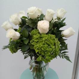 White roses and green hydrangeas in a clear glass vase
