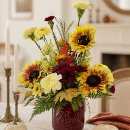Sunflower and carnation arrangement in a red mason jar vase