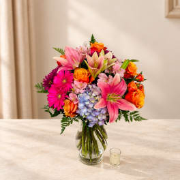 Colorful bouquet of lilies, roses, gerbera daisies, and hydrangeas in a glass vase