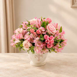 Pink roses and lilies arranged in a white ceramic vase