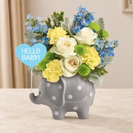 Blue and yellow flower arrangement in a gray elephant vase with a "Hello Baby!" sign