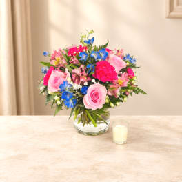 Pink and blue mixed bouquet in a clear glass vase on a table