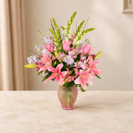 Pink lilies and roses arranged in a frosted glass vase