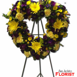 Heart-shaped floral wreath on a standing easel with yellow and purple flowers