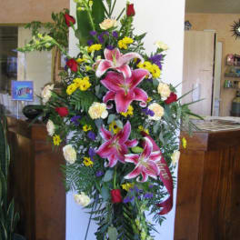 Tall standing floral spray with pink lilies, red roses, and yellow accents